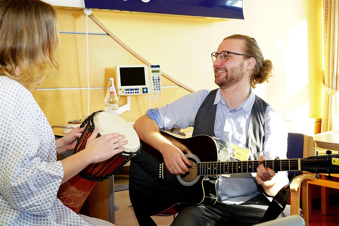 Music therapy at the bedside: Henrik Vorbröker playing guitar for a client
